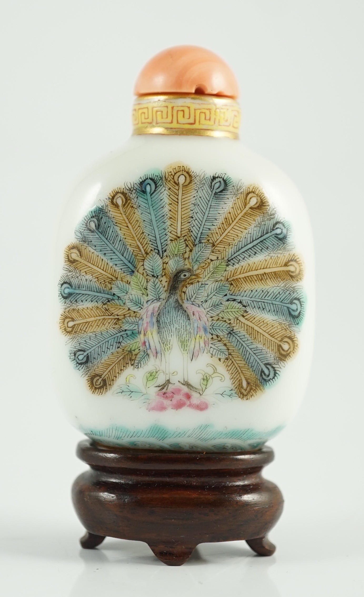 A Chinese enamelled porcelain ‘peacock and dragon’ snuff bottle, Jiaqing mark and period (1796-1820), 5.6cm high, coral stopper and wood stand